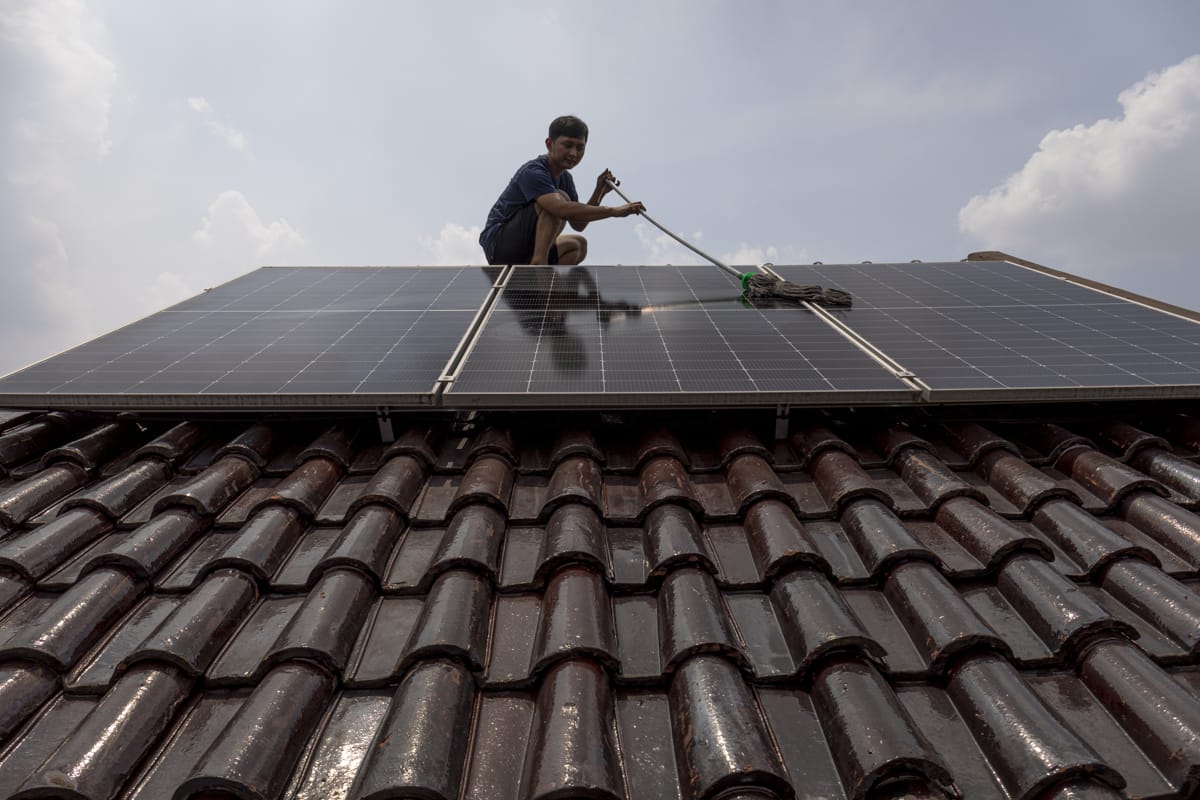 Climate and energy campaigner Hadi Priyanto cleaning solar panels on his home in Depok City, West Java, Indonesia, 17 November 2023 (Aji Styawan/Climate Visuals, CC BY-NC-ND 4.0 - main image also courtesy the same website)