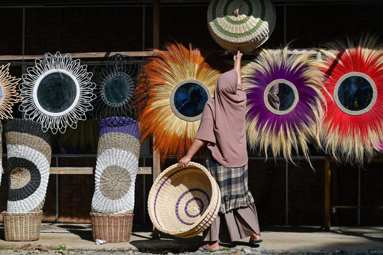 A shopkeeper hangs merchandise for sale at a handicrafts shop in Lhoknga, Aceh province (Chaideer Mahyuddin/AFP via Getty Images)
