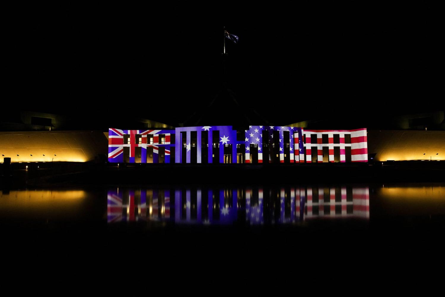 The Australian Parliament House is lit up with both the Australian and US flags to celebrate the 70th anniversary of the ANZUS Treaty in Canberra on 27 March 2022 (Gary Ramage/AFP via Getty Images)