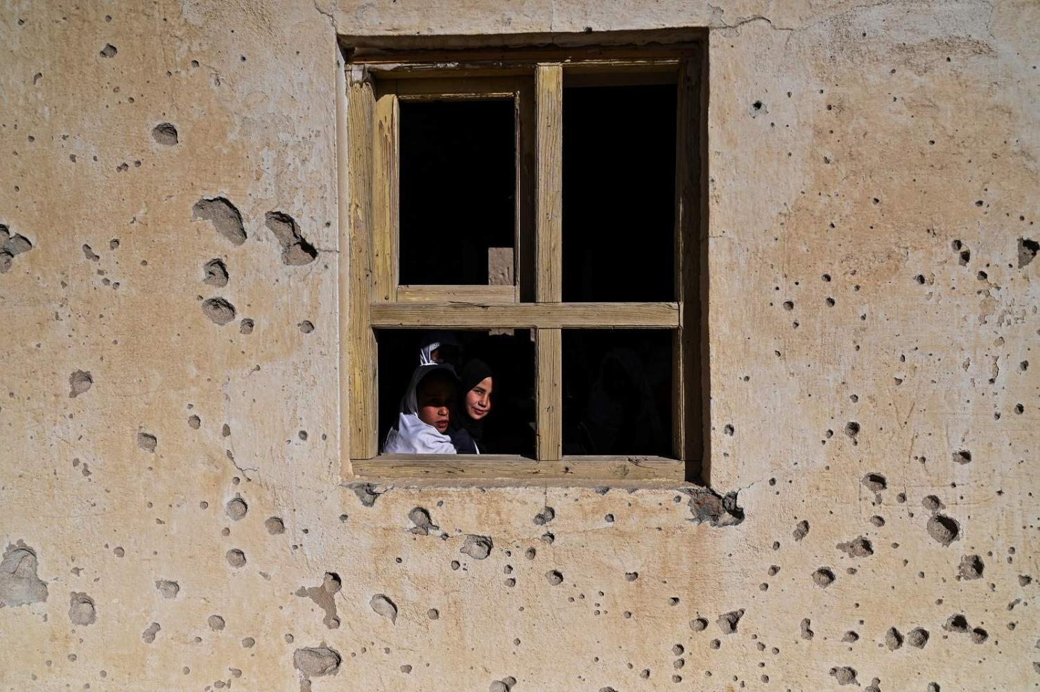 Girls attend class at their bullet-riddled school in Arzo village on the outskirts of Ghazni, Afghanistan, 16 November 2021 (Hector Retamal/AFP via Getty Images)