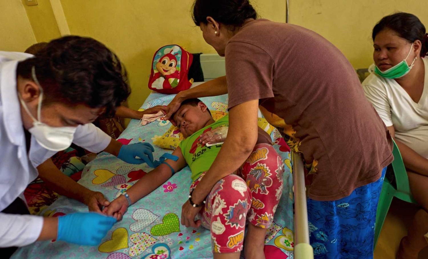 A 6-year-old boy is comforted by his mother as a nurse extracts blood for testing at the San Lazaro Hospital, Manila, 14 August 2019 (Photo: Jes Aznar/Getty Images)