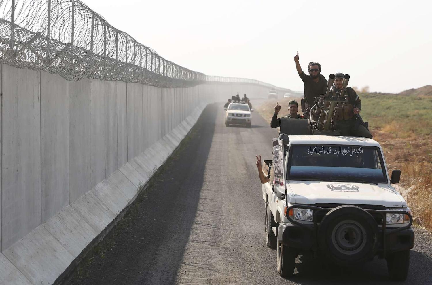 Turkey-backed Syrian fighters travel along the border between Syria and Turkey near the border town of Ras al-Ain in the Hassakeh province in northeastern Syria, 27 October (Photo: Nazeer al-Khatib/AFP/Getty Images)