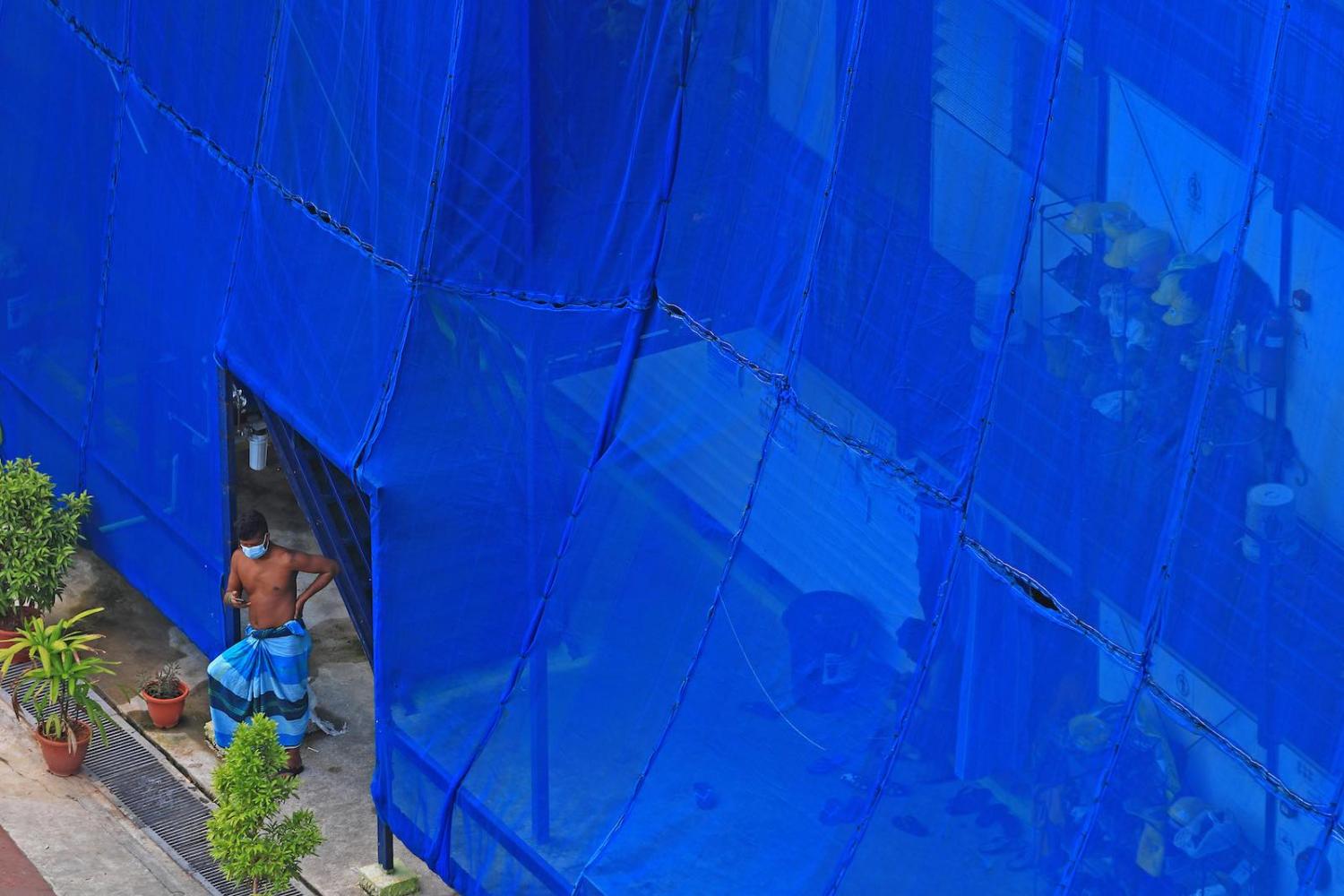 A migrant worker stands outside a makeshift dormitory room at a stalled construction site in Singapore in May (Suhaimi Abdullah/Getty Images)