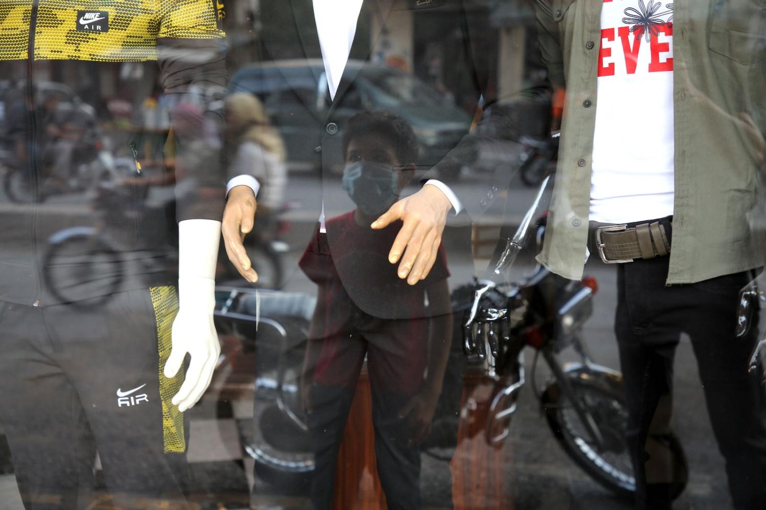 A boy stands in front of a clothing store in Idlib, north-western Syria, 11 July 2020 (Muhammad al-Rifai/NurPhoto via Getty Images)