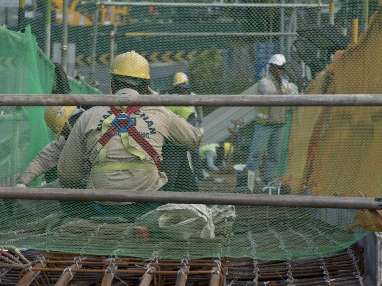 Migrant workers at a construction site by a highway in Singapore (Majority World/Universal Images Group via Getty Images)