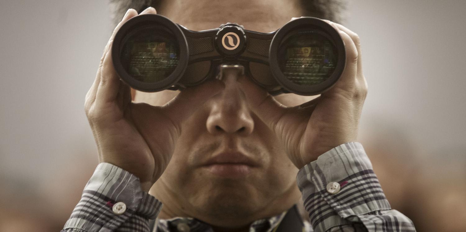A man uses a pair of binoculars during the closing ceremony of the NPC, March 2017 (Photo: Getty Images/Bloomberg)